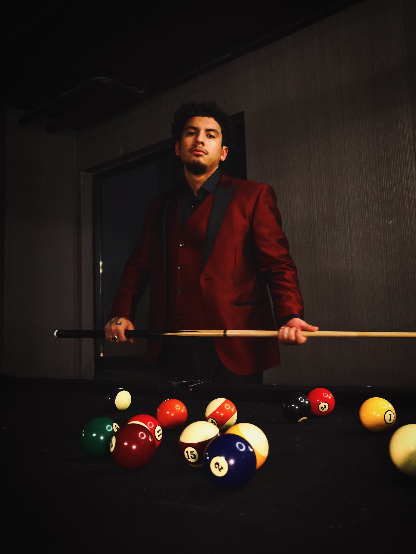 Dnd in a red suit leaning over a pool table