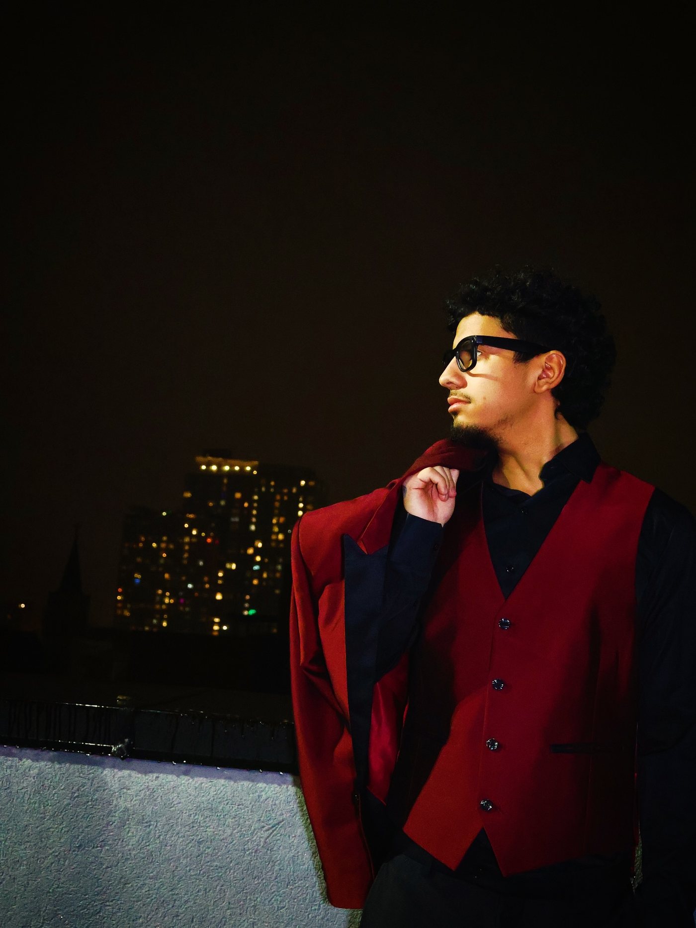 Dnd in a red vest with the New York skyline behind him